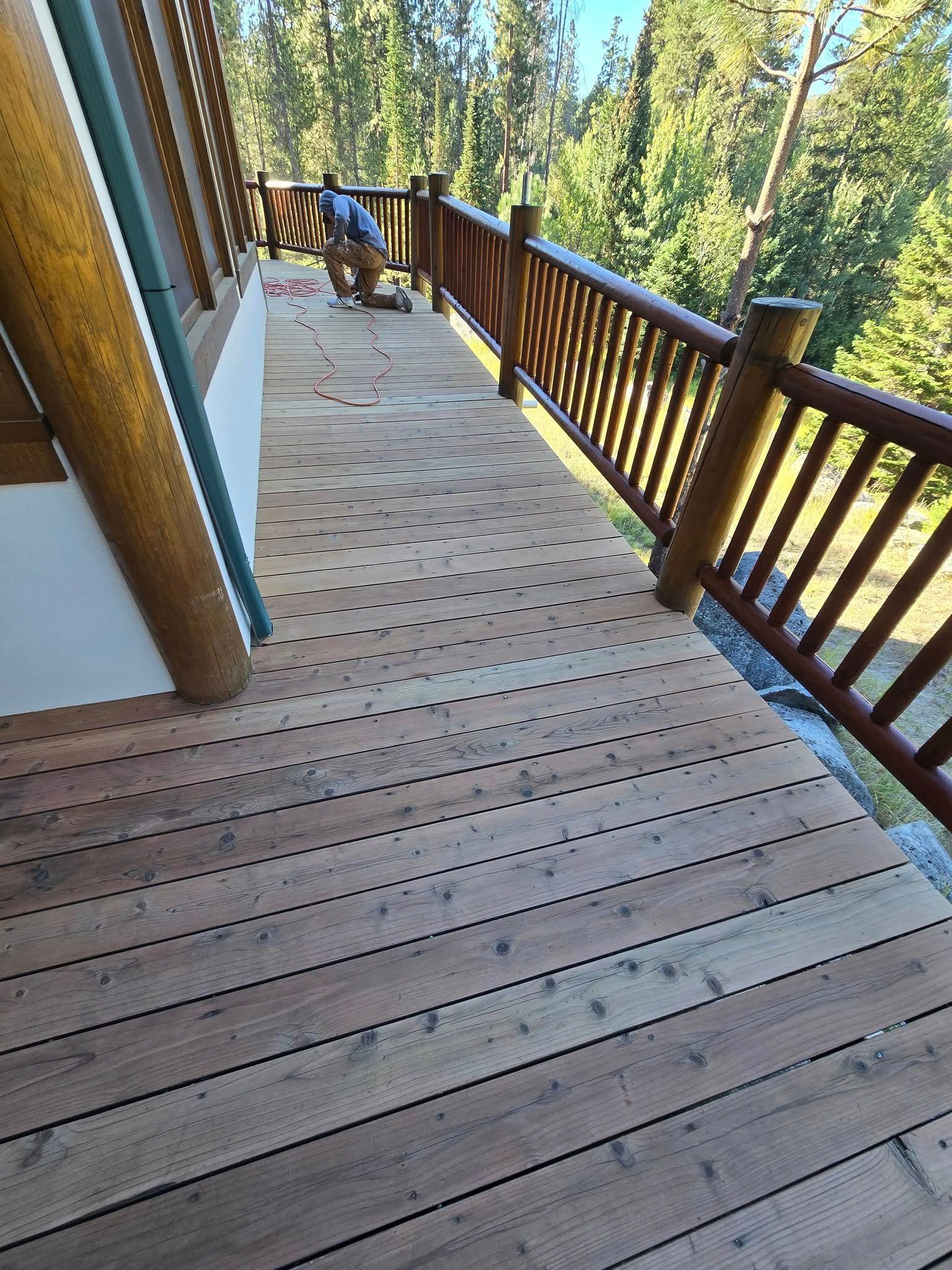 Wooden deck with railing, person working. Forest background.