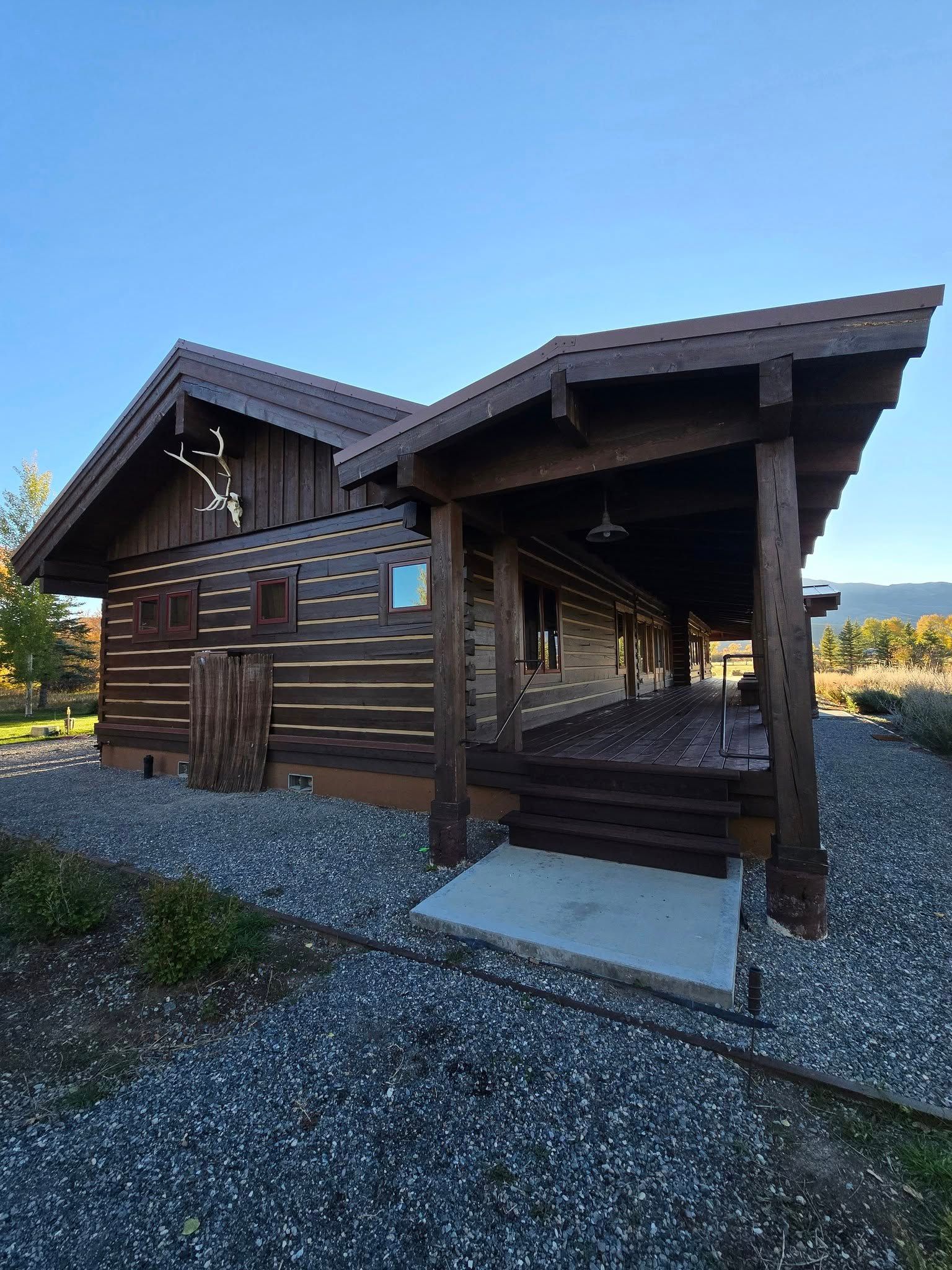Log cabin with dark brown wood siding and a covered porch.