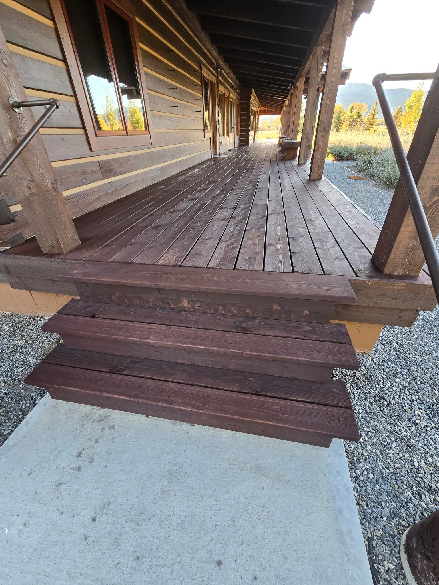 Wooden porch and steps leading to a log cabin with a concrete landing.