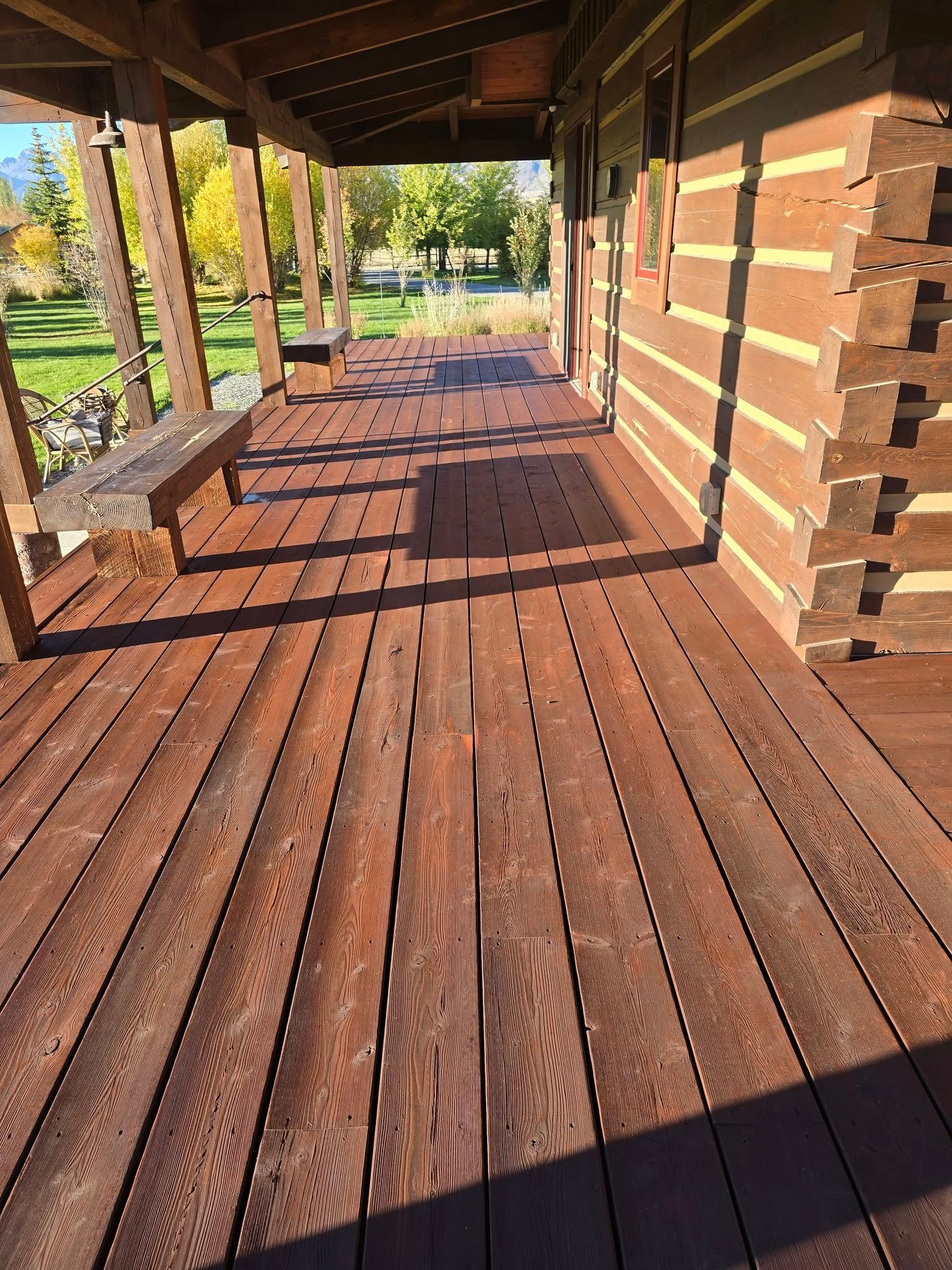 Wooden porch with bench on the left, next to a log cabin wall.