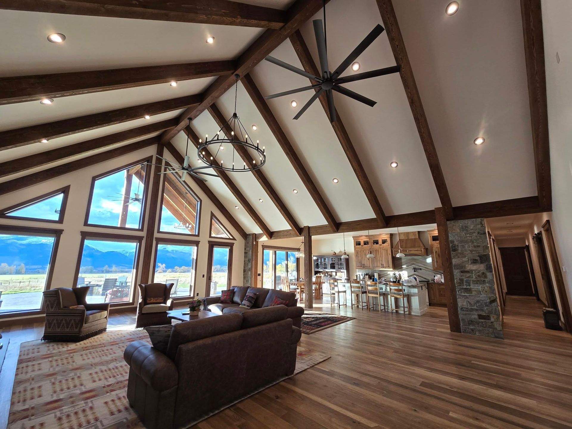 Spacious living room with wood beams, high ceilings, large windows, and a leather sofa.