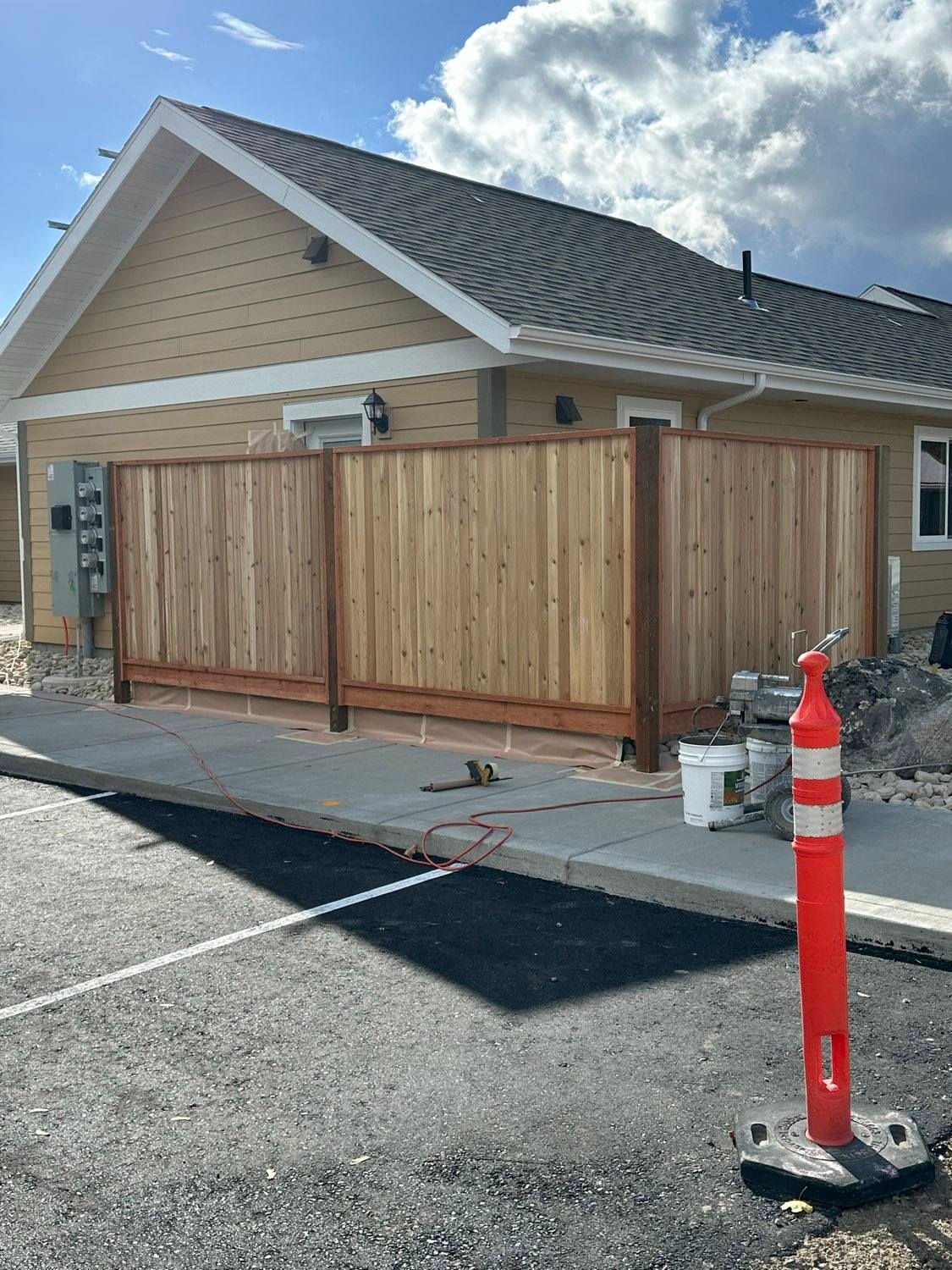 New wooden privacy fence installed near a tan building and a parking lot.