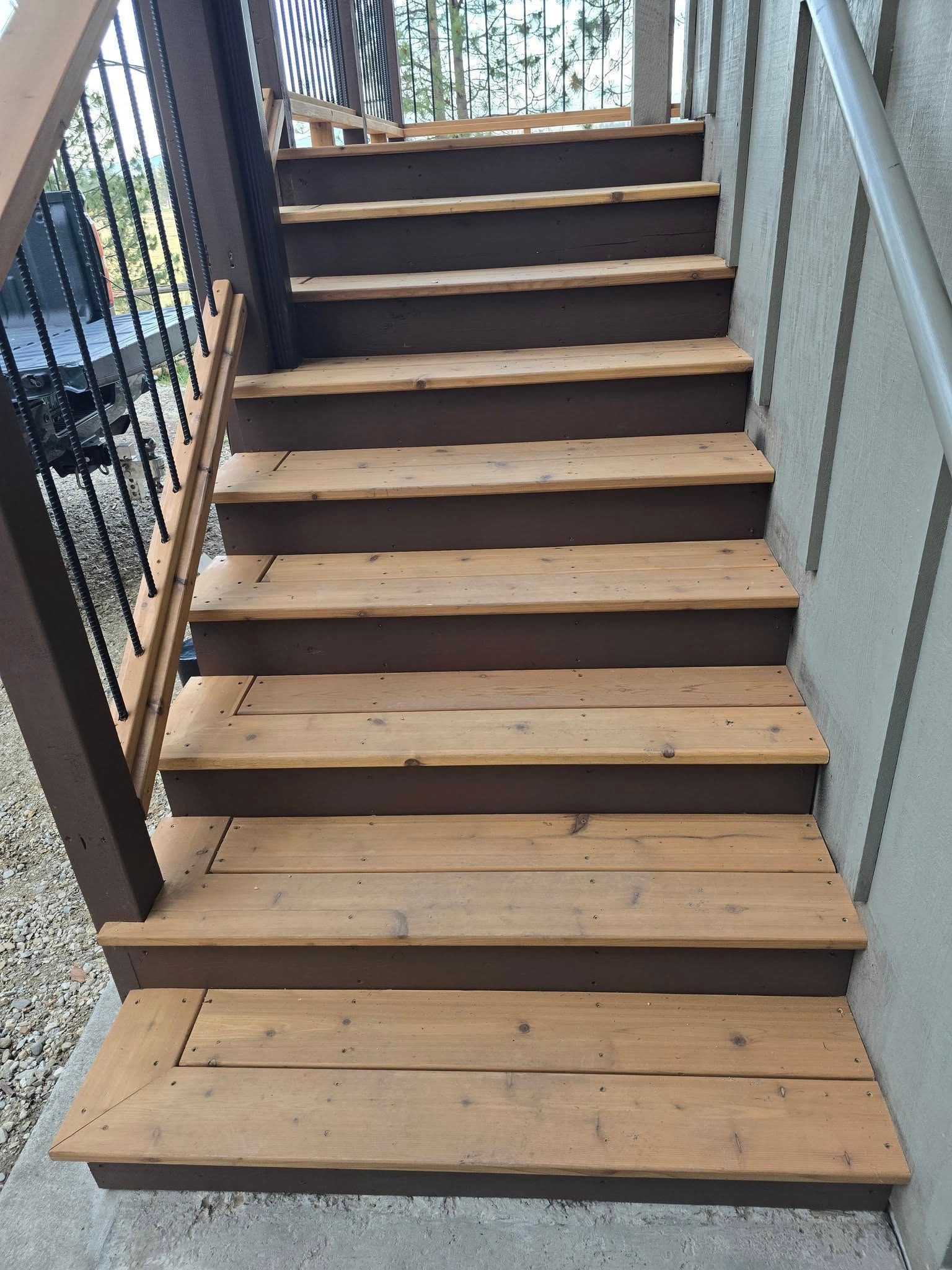 Wooden outdoor staircase with brown trim and light wood steps. Railing on the left and right.