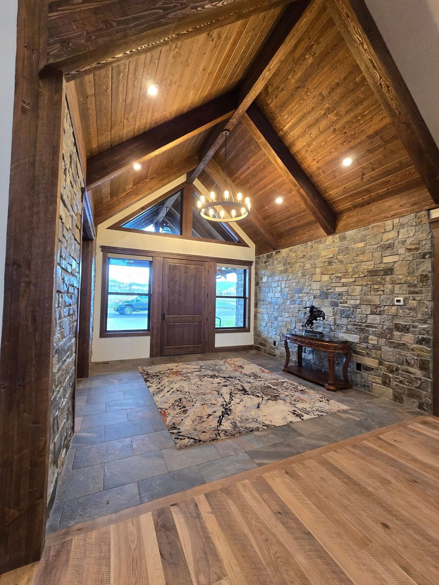 Rustic entry hall with stone walls, wooden ceiling, and a rug.