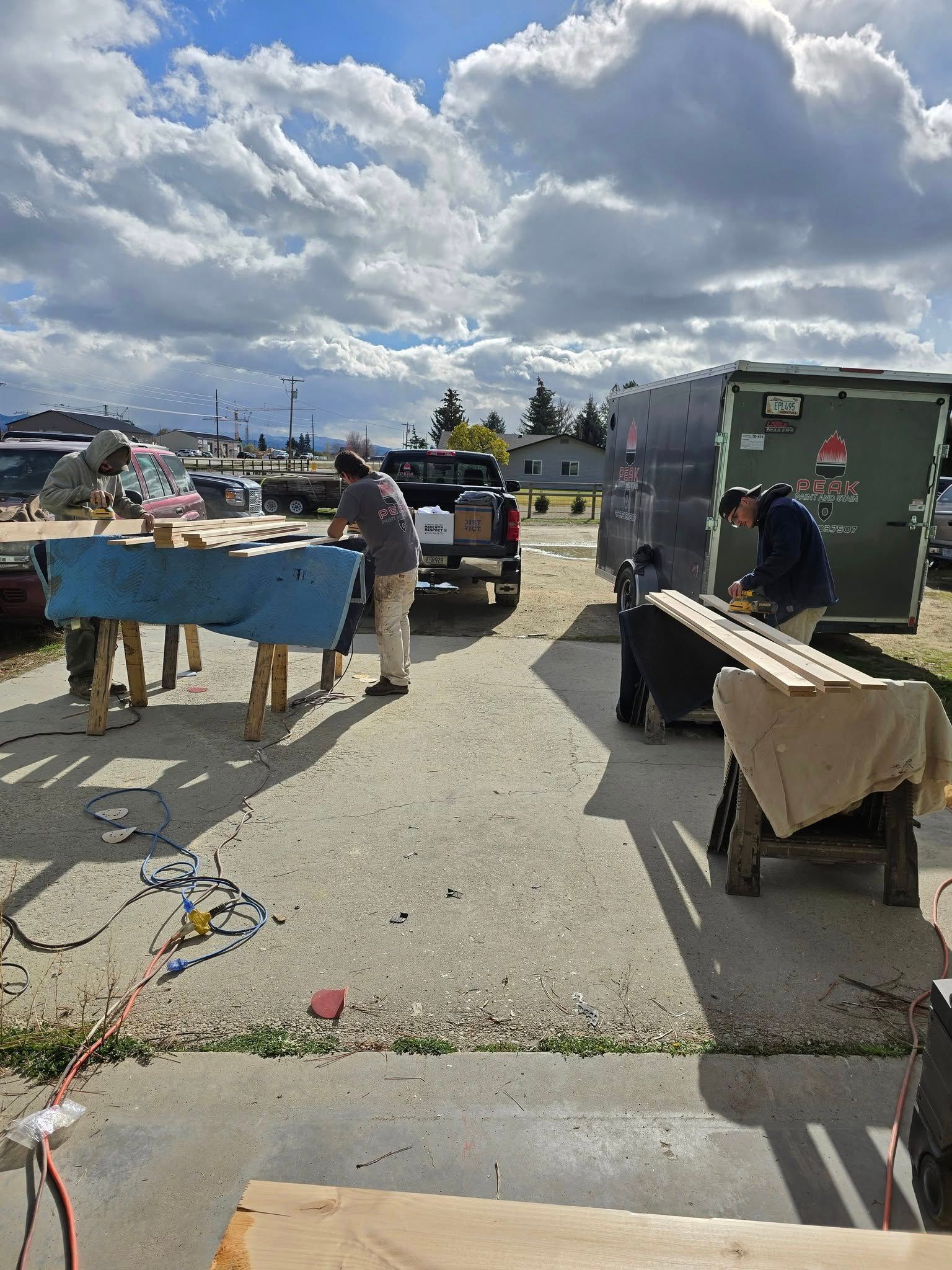Several people working on wooden boards outdoors on a sunny day.