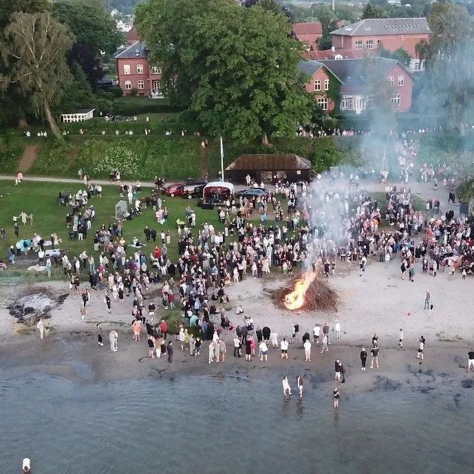 Luftfoto af Sankt Hans-bål med menneskemængde i Præstø
