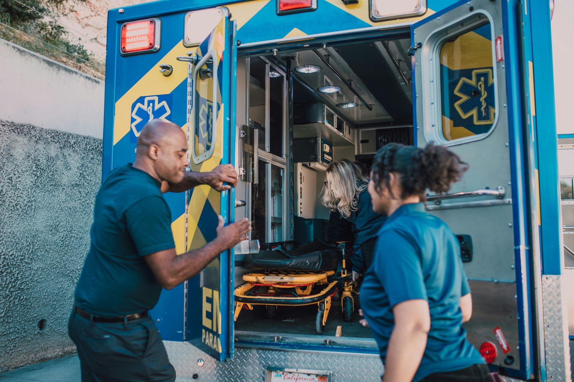 Two EMTs load stretcher into the back of an ambulance.
