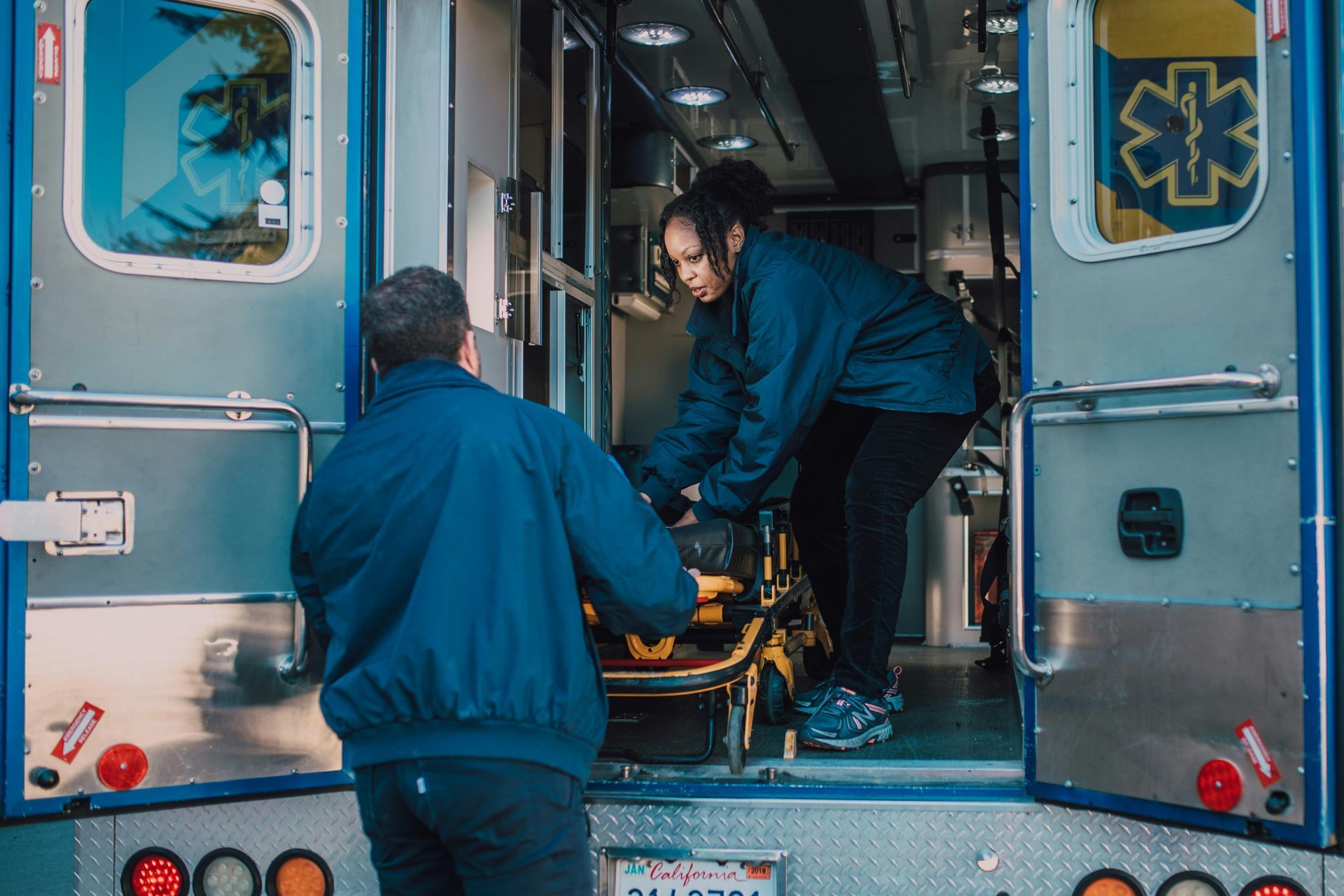 Two EMTs load a stretcher into an ambulance.