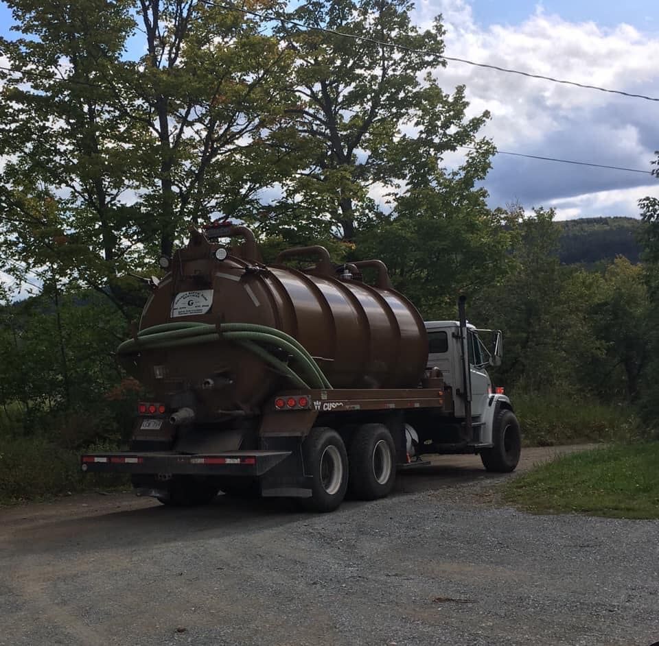 A vacuum truck is parked on the side of the road