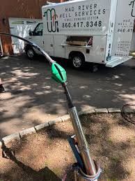 A green trash grabber stands beside a sidewalk near a parked white service truck.