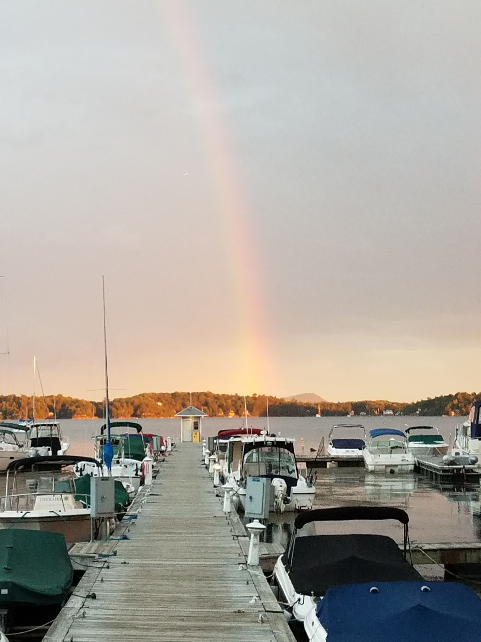 A dock filled with boats and a rainbow in the sky