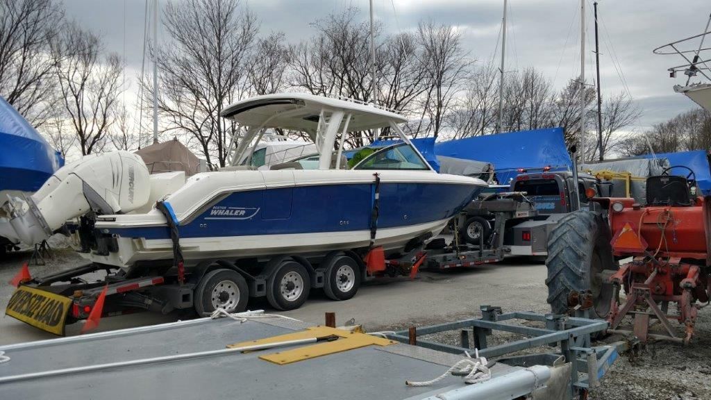 A boat is being transported on a trailer in a parking lot.