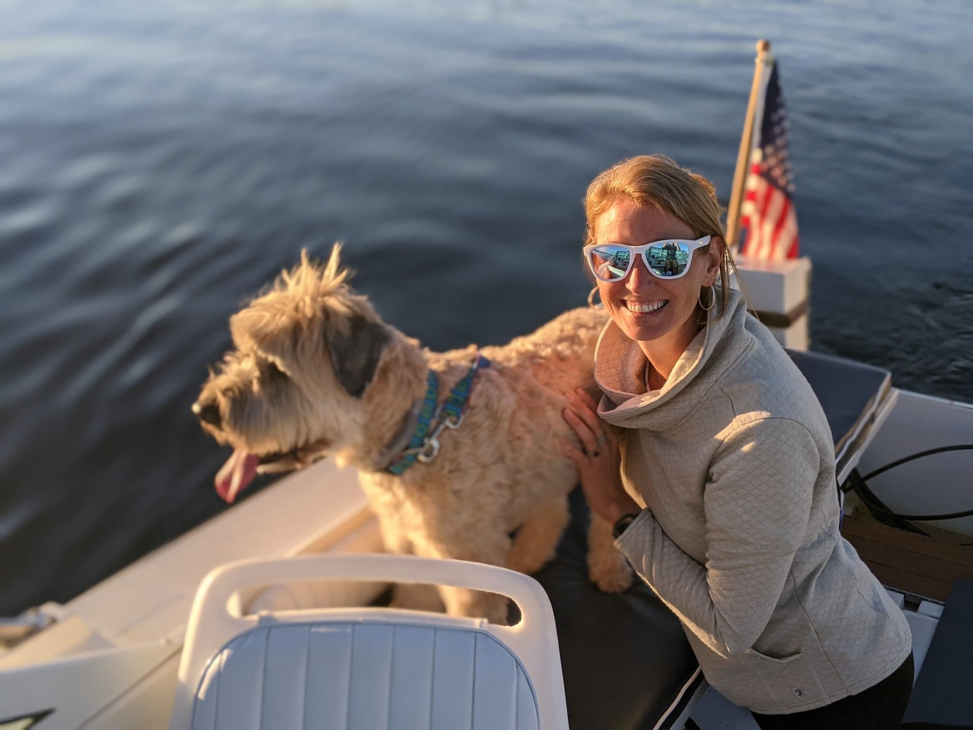 A woman is sitting on a boat with her dog