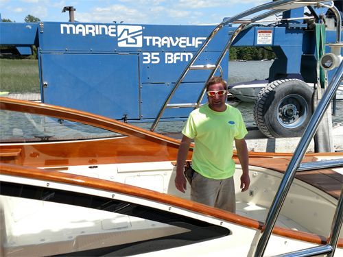 A man is standing in front of a marine travelif 35 bfm machine