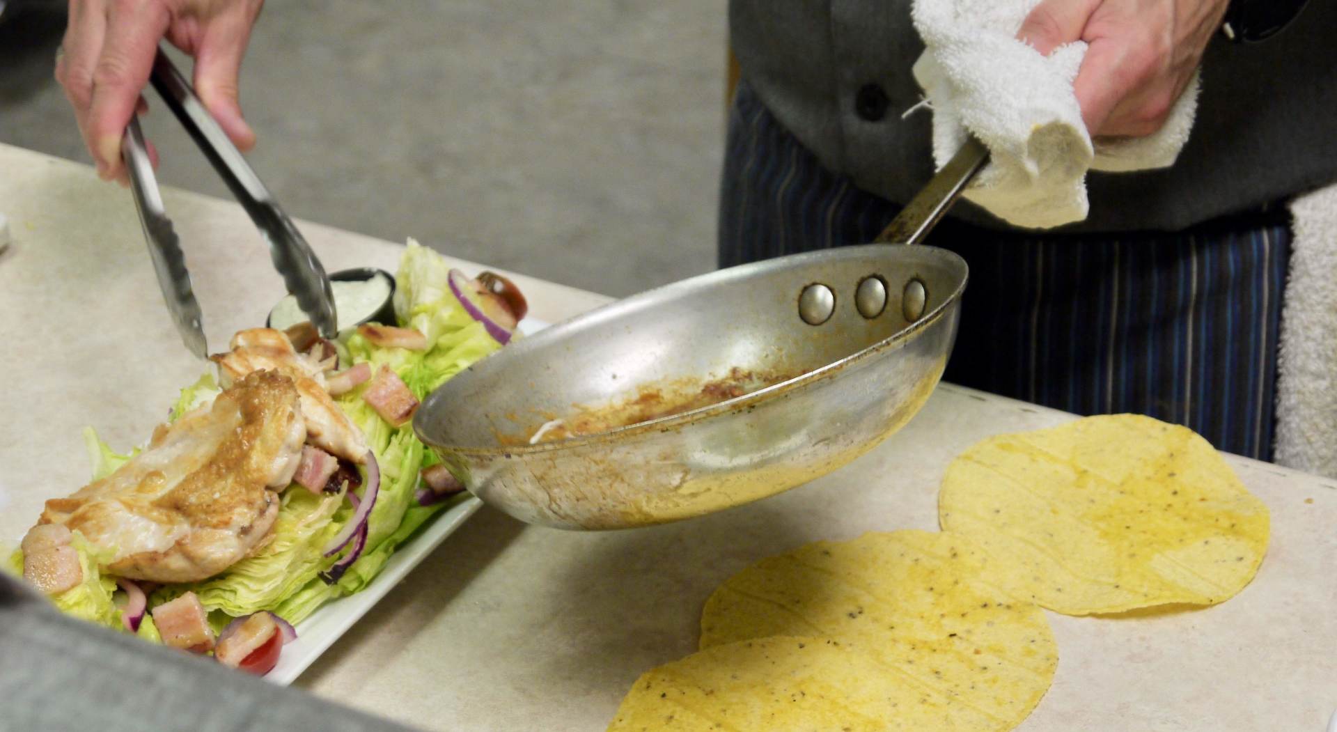 A person is cooking food in a pan on a table.