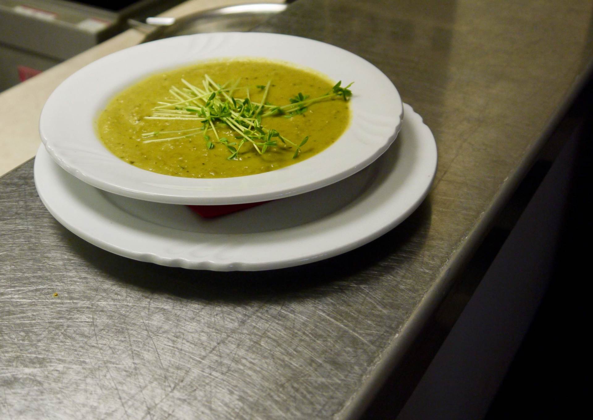 A bowl of soup on a plate on a counter
