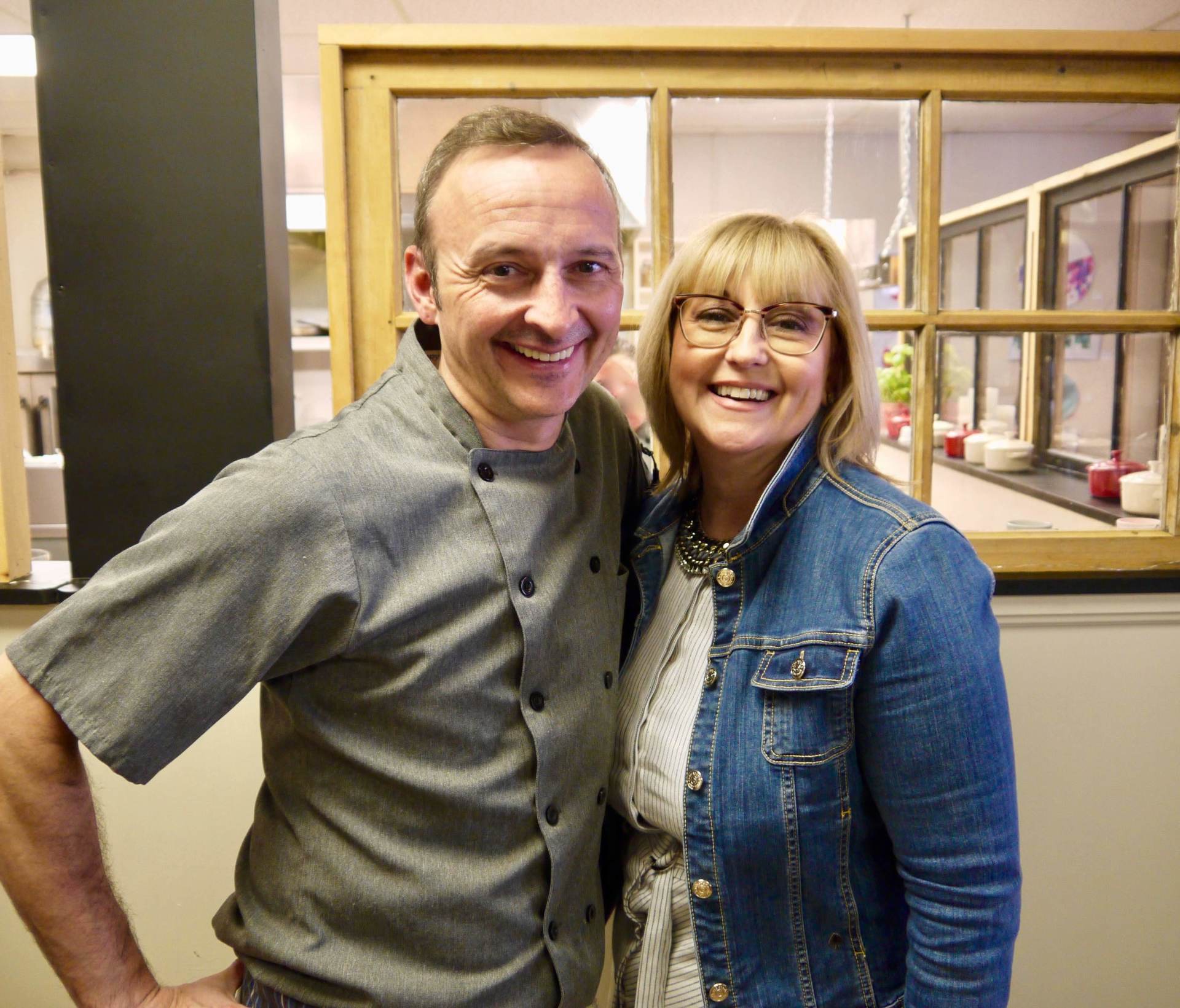 A man and a woman are posing for a picture in front of a window.