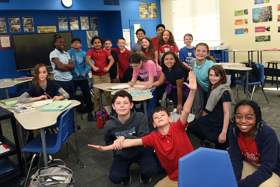 a group of children pose for a picture in a classroom with a sign on the wall that says boarding method