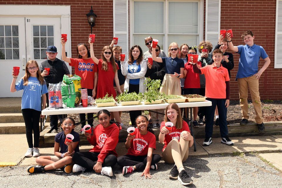 a group of children holding up red cups in front of a building with the number 81 on it