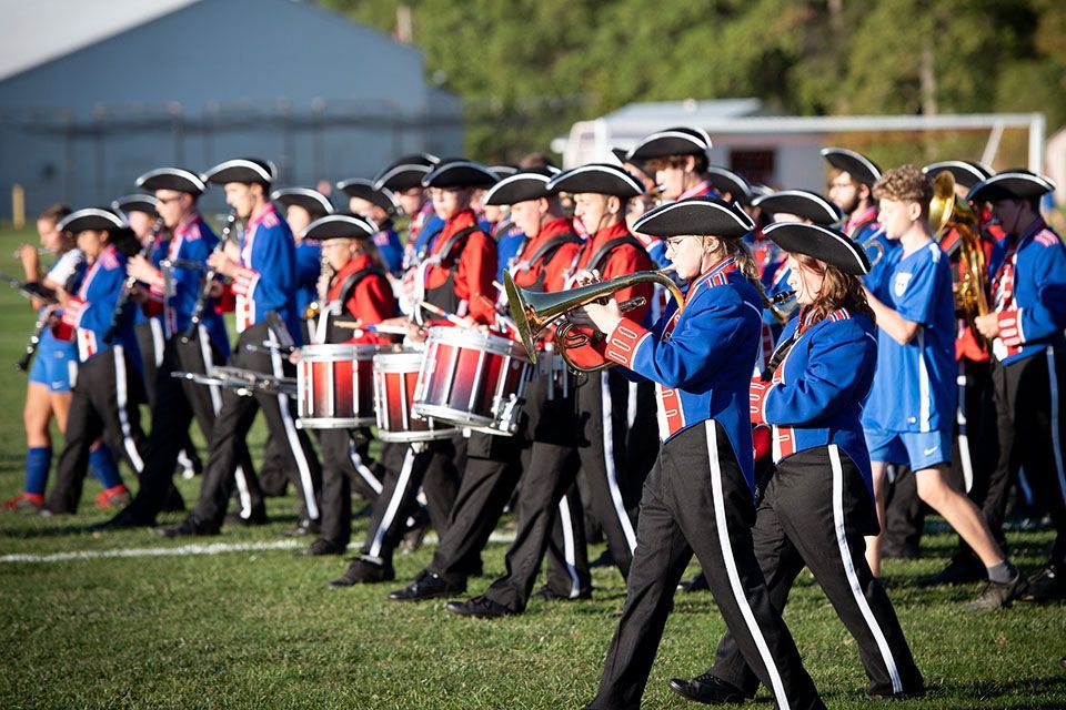 a marching band is marching down a field with drums and trumpets