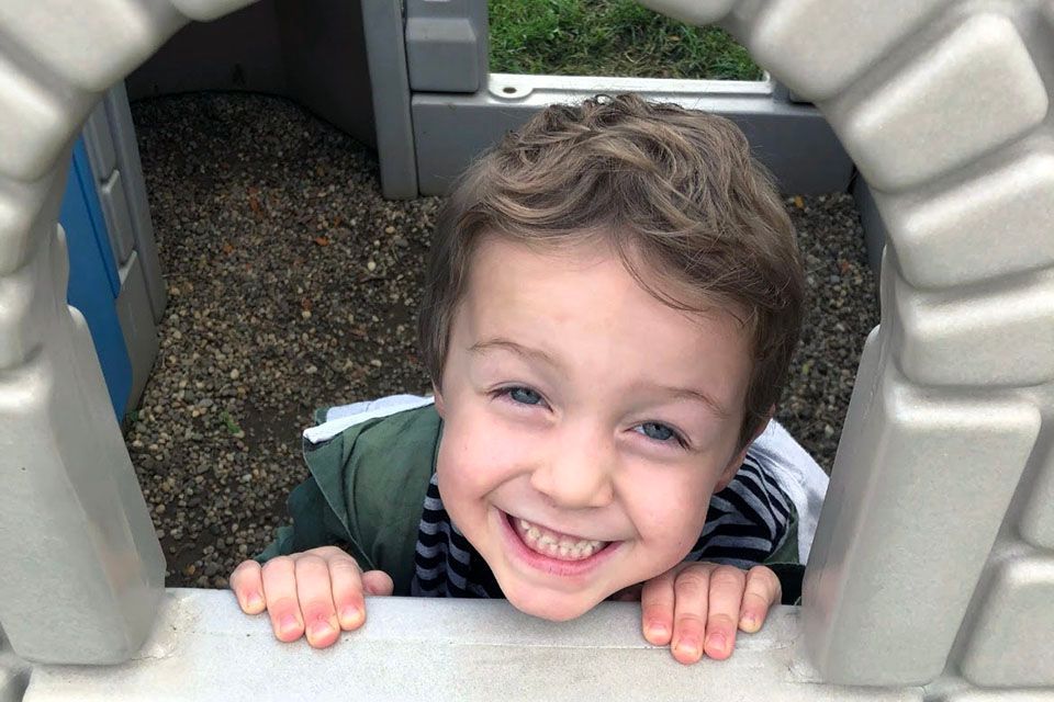 a young boy is smiling while looking out of a playhouse