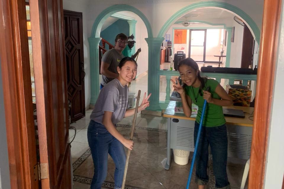 Students are cleaning a room with a mop.