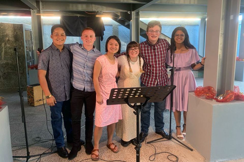 Students posing for a picture in front of a microphone and music stand.