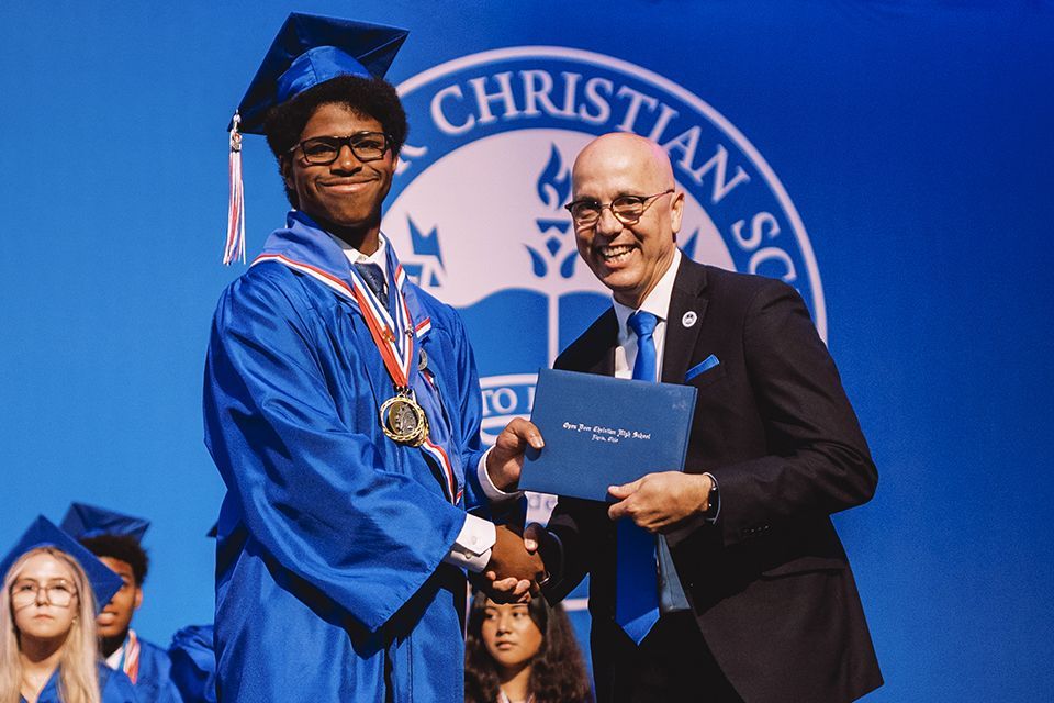 A graduate poses with Denver Daniel, ODCS President.