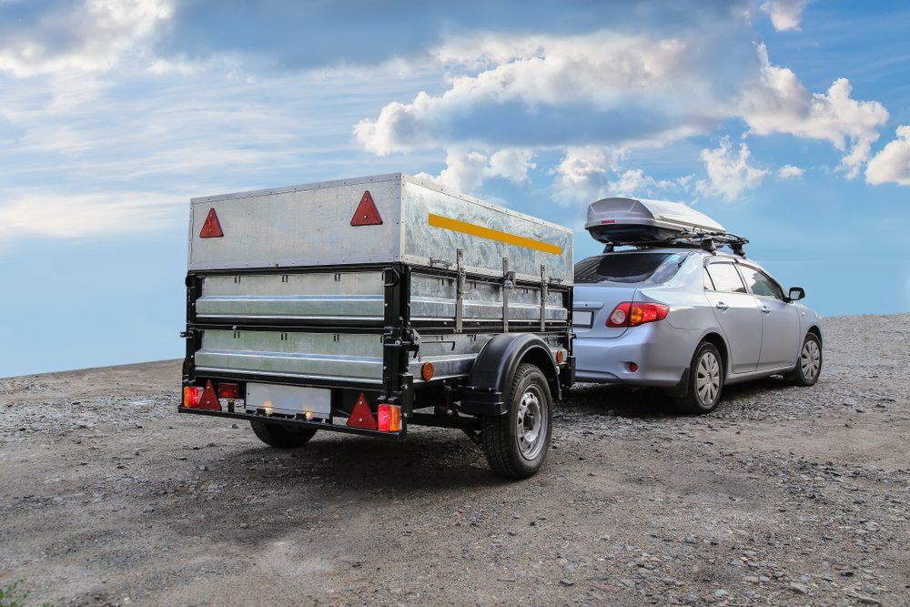 A Car Is Towing a Trailer on A Dirt Road — Emu Park Automotive and Tyre Service in Emu Park, QLD