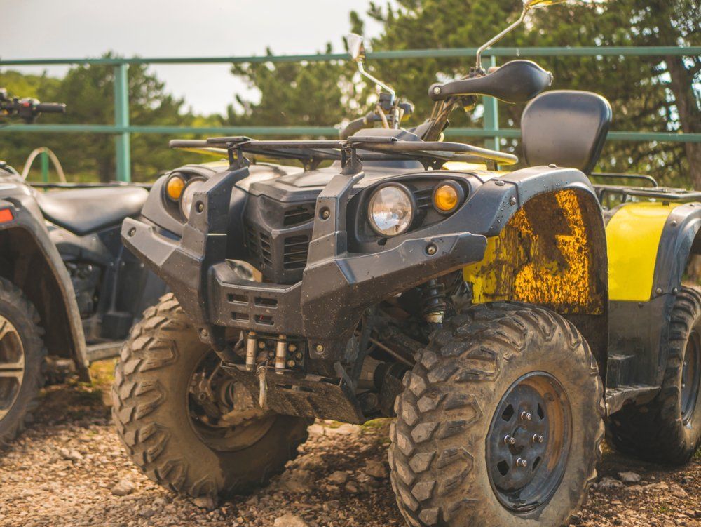 A Black and Yellow Atv Is Parked Next to A Black ATV