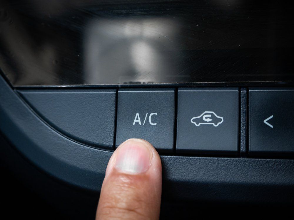 A Person Is Pressing the A / C Button on A Car Dashboard — Emu Park Automotive and Tyre Service in Emu Park, QLD