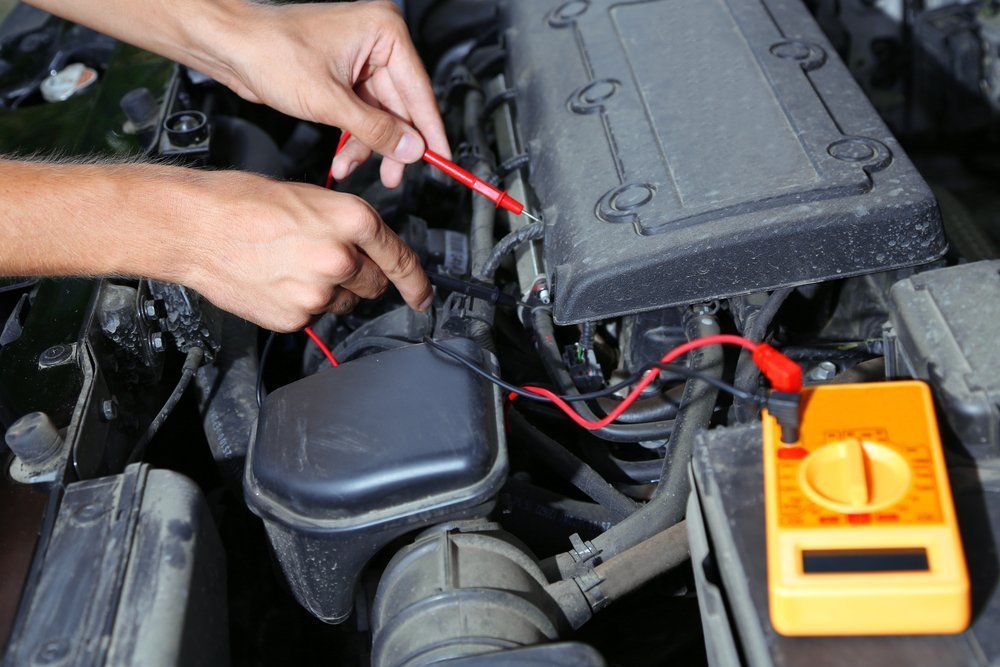 A Person Is Working on A Car Engine with A Multimeter — Emu Park Automotive and Tyre Service in Emu Park, QLD