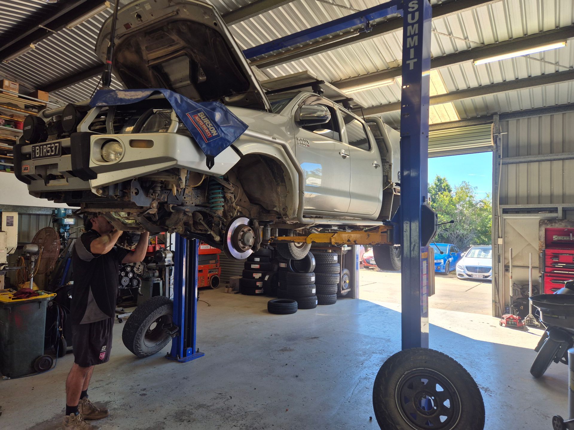 Silver Pickup Truck Lifted on a Blue Hoist in an Auto Shop — Emu Park Automotive and Tyre Service in Emu Park, QLD