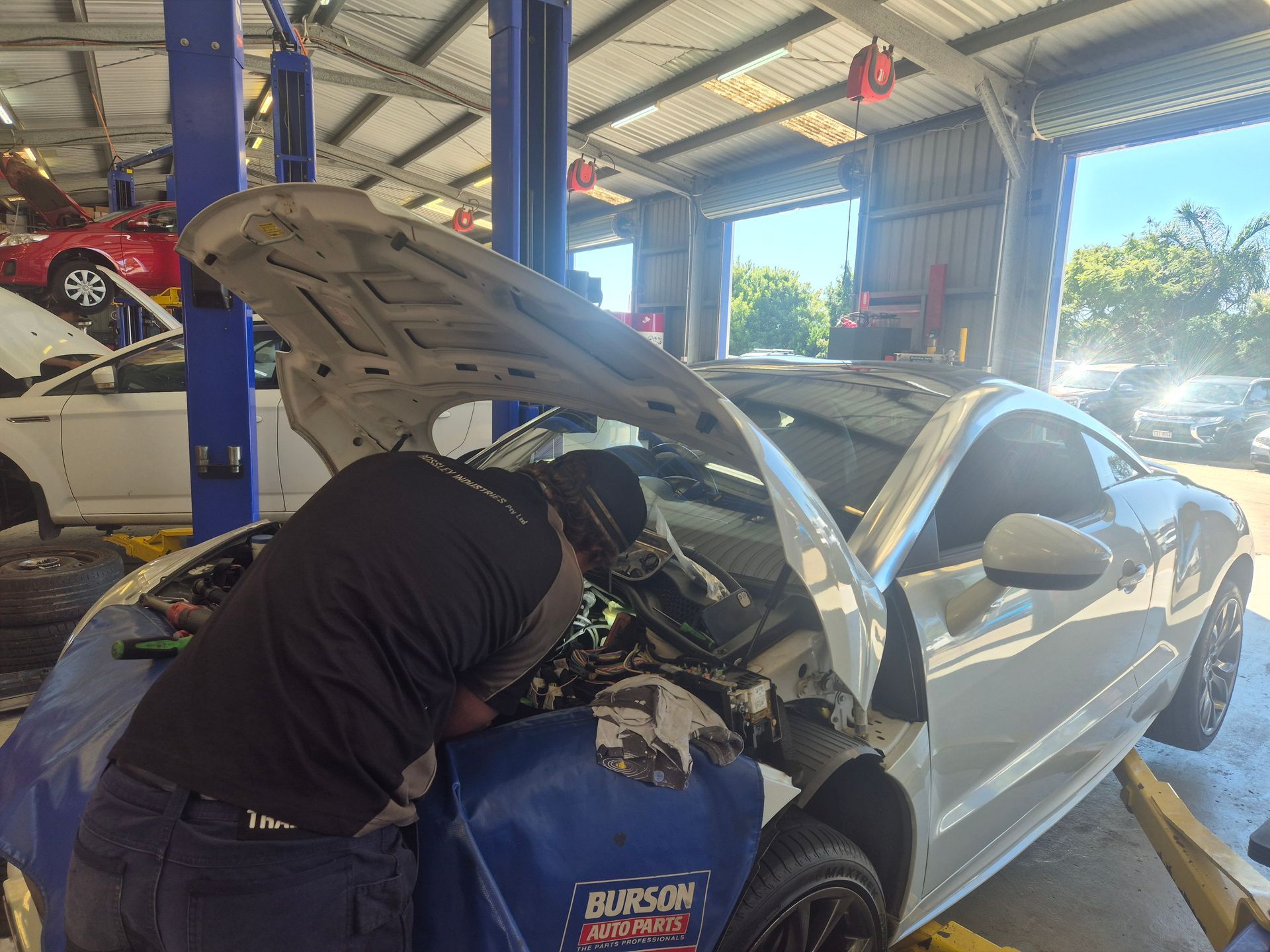 Mechanic Working Under Open Hood of a Silver Car — Emu Park Automotive and Tyre Service in Zilzie, QLD