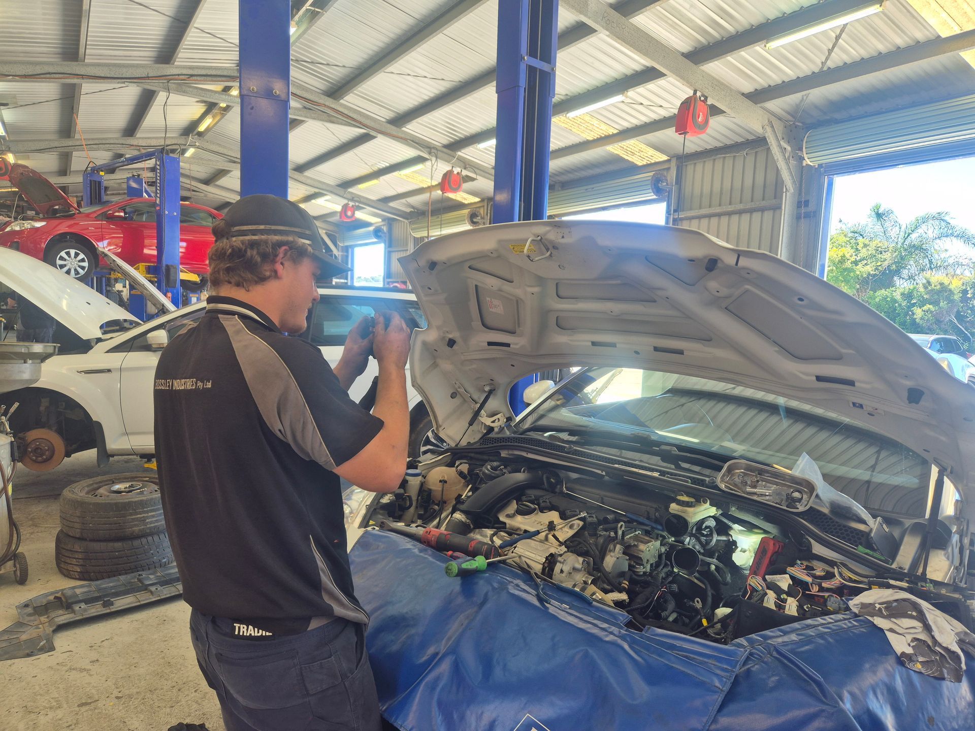 Mechanic inspecting an open car engine in a garage workshop  — Emu Park Automotive and Tyre Service in Emu Park, QLD