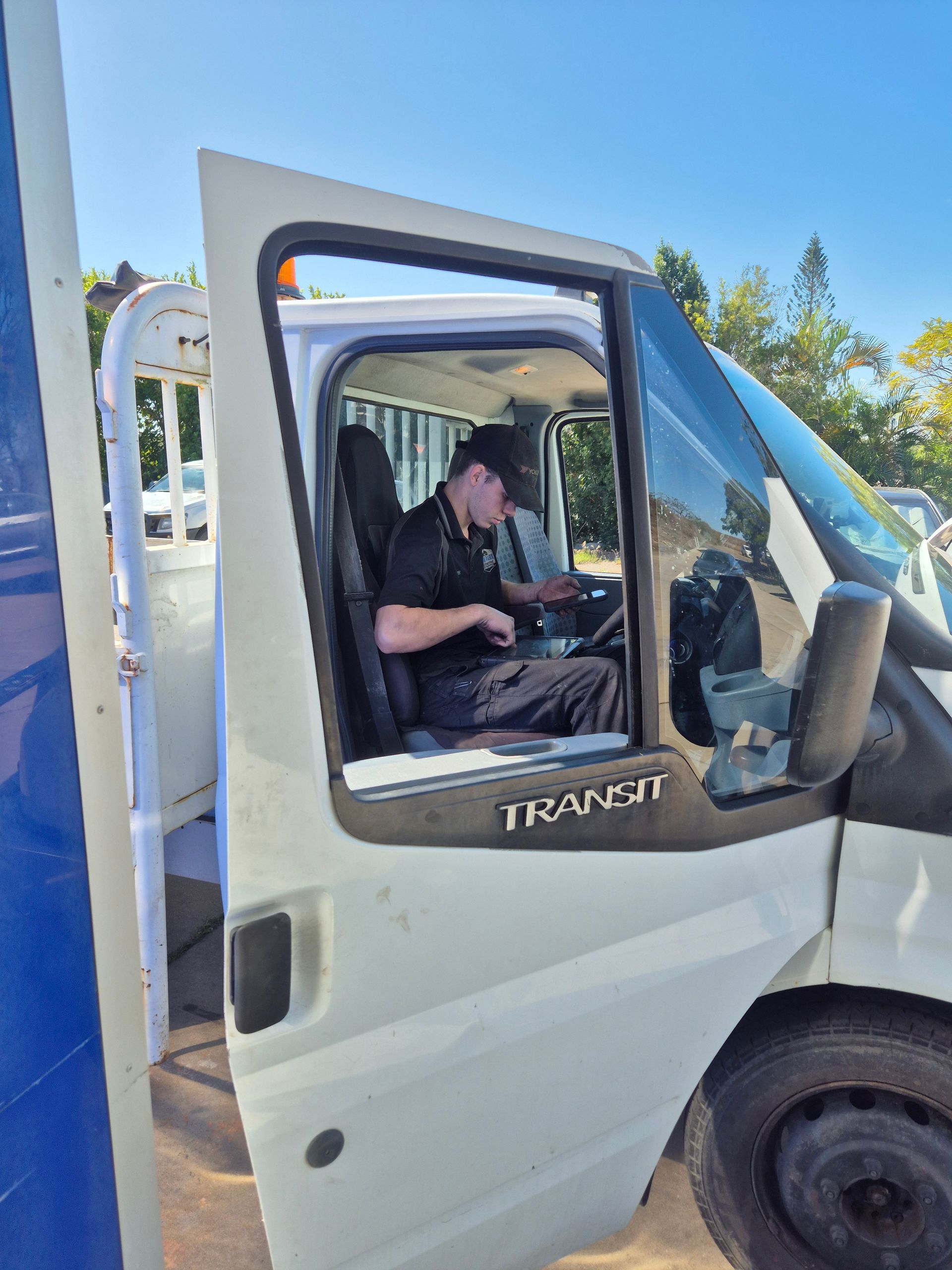 Man in the driver’s seat of a white truck with the door open, parked outdoors in bright sunlight. — Emu Park Automotive and Tyre Service in Keppel Sands, QLD