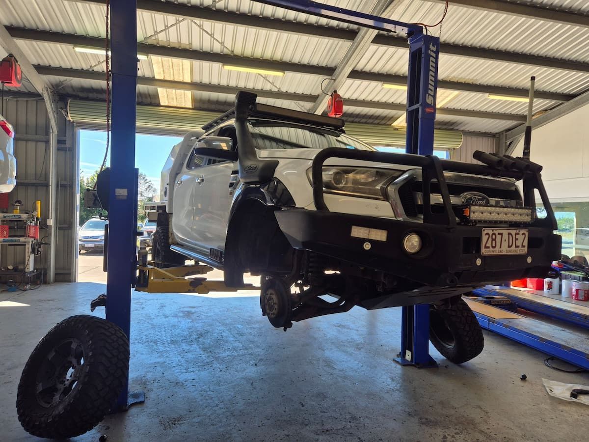 Car Lifted in a Garage With Front Bumper Removed — Emu Park Automotive and Tyre Service in Cooee Bay, QLD