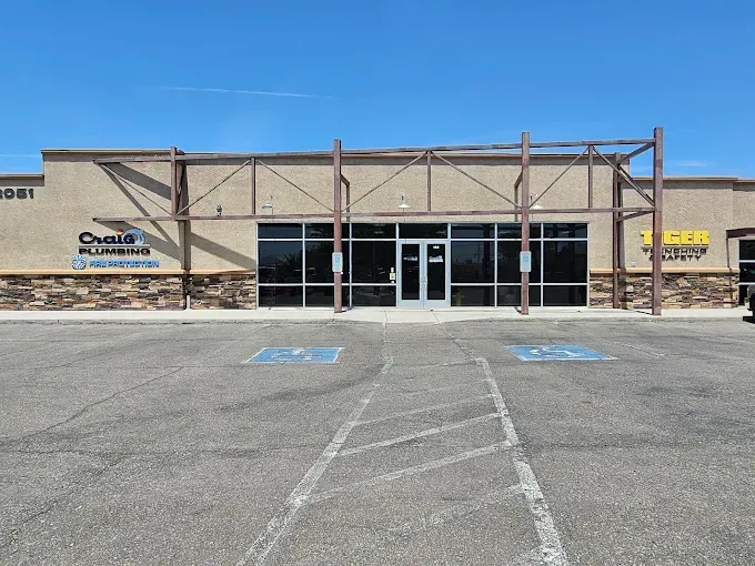 Exterior view of a commercial building with large windows and a brown facade, blue sky.