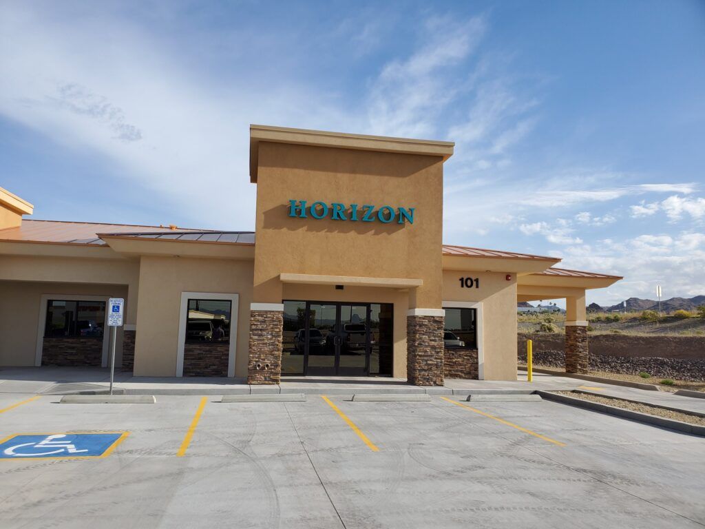 Exterior view of a Horizon building with a blue sky, accessible parking, and light brown stucco.