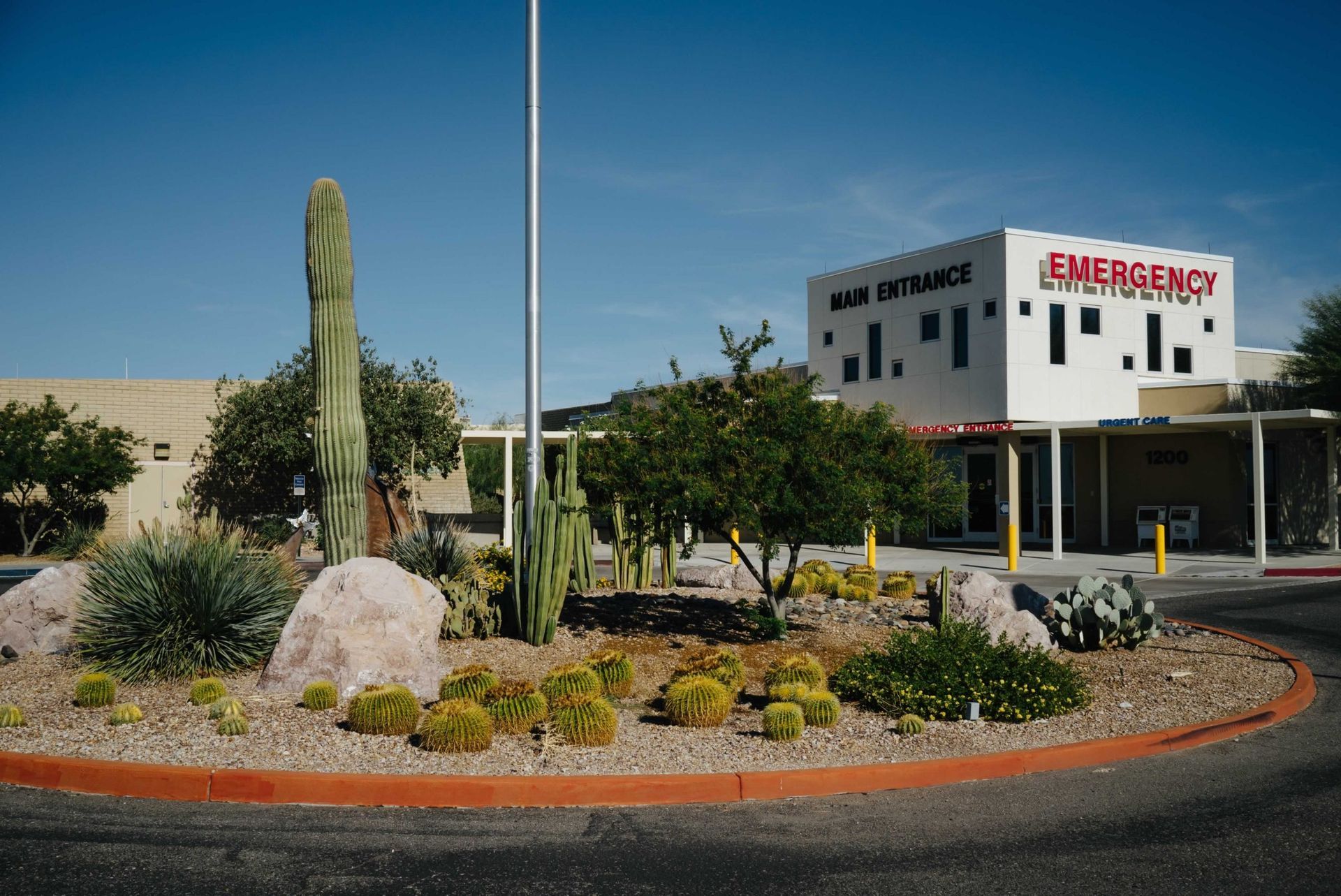 Hospital emergency entrance with desert landscaping under a blue sky.
