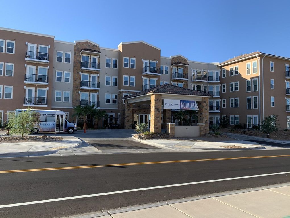 Multi-story apartment building with covered entrance, bus parked in front.