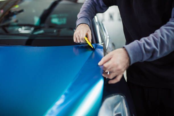 A man is applying window tinting to a car window.