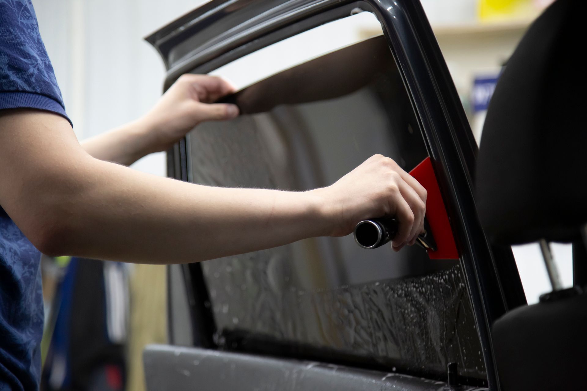 A person is applying window tinting to a car window.