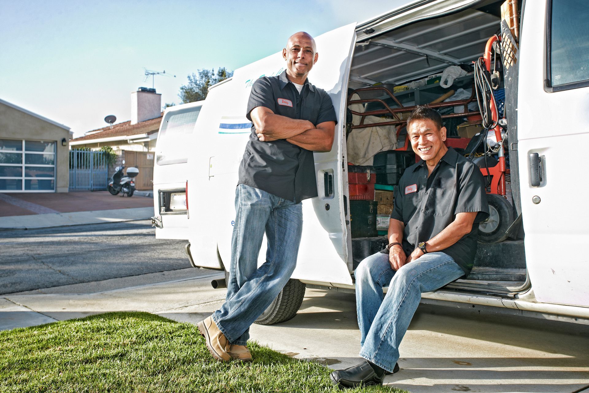 Professional plumbers standing beside service van with plumbing tools and repair equipment.