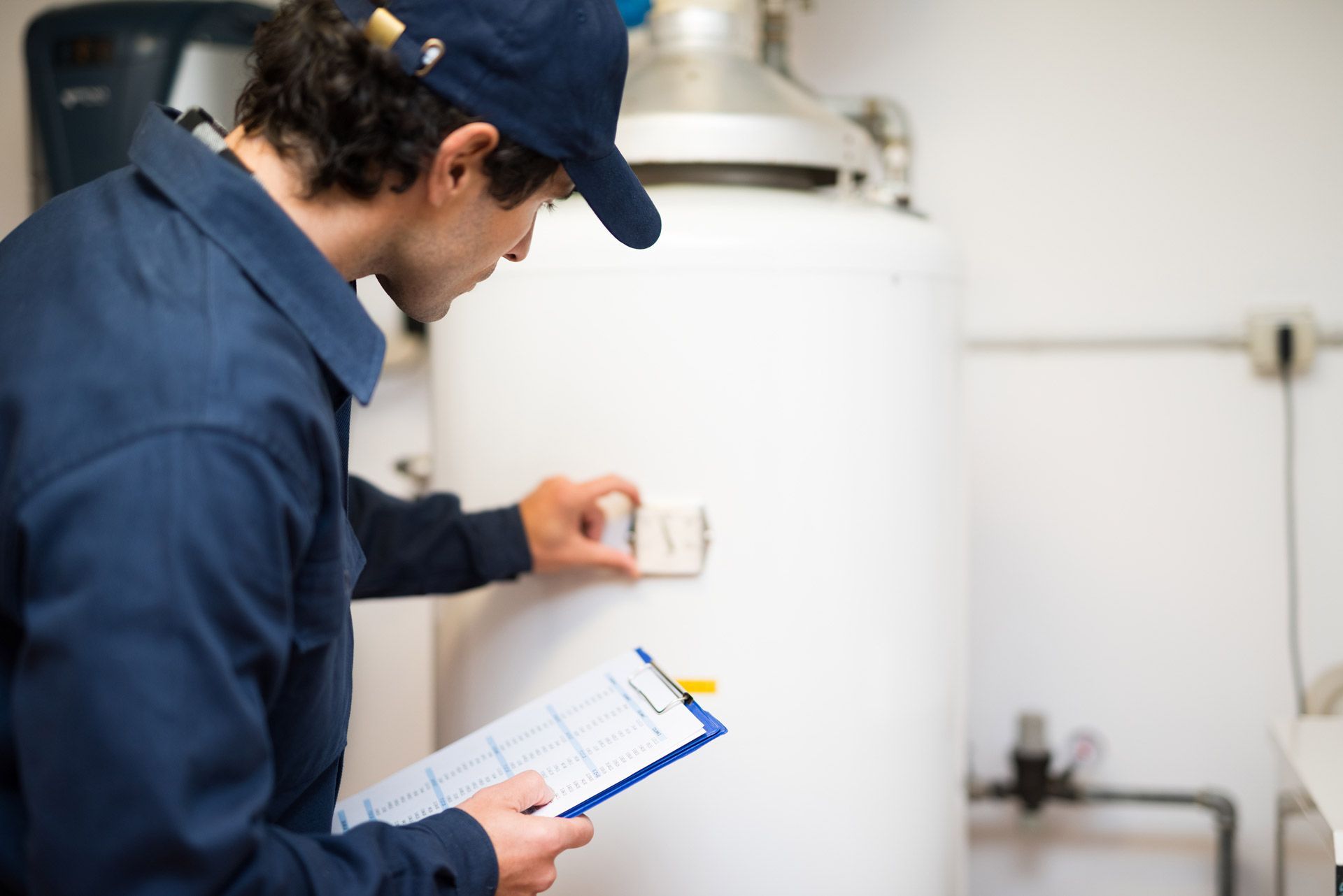The technician inspects the water heater, adjusting controls with a checklist clipboard.