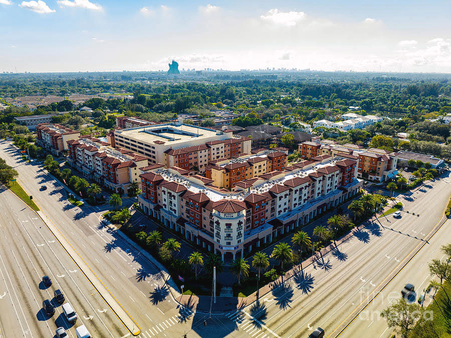 An aerial view of a large apartment complex surrounded by trees and a highway.