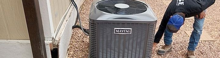 A man is working on an air conditioner outside of a house.