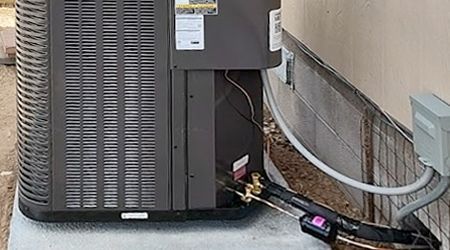 An air conditioner is sitting on the side of a building next to a wall.