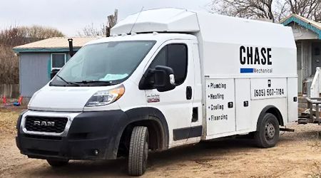 A white chase van is parked in front of a house.