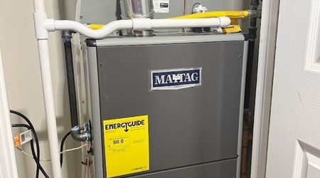 A gray heater is sitting in a room next to a door.